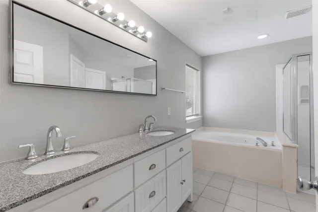 a bathroom with a granite countertop bathtub sink vanity and mirror