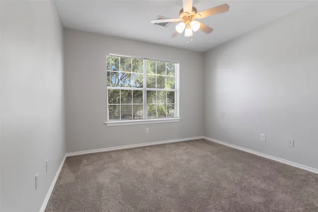 an empty room with a window and a fan