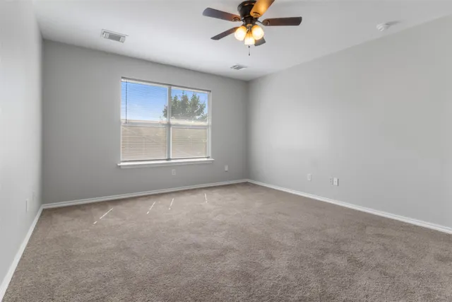 an empty room with a window and a fan
