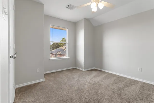an empty room with windows and fan