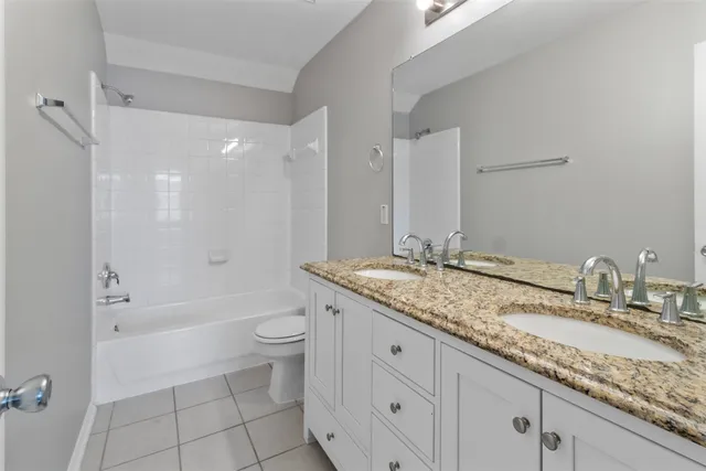 a bathroom with a granite countertop toilet a sink and a bathtub