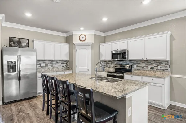 a kitchen with stainless steel appliances granite countertop a stove refrigerator and microwave