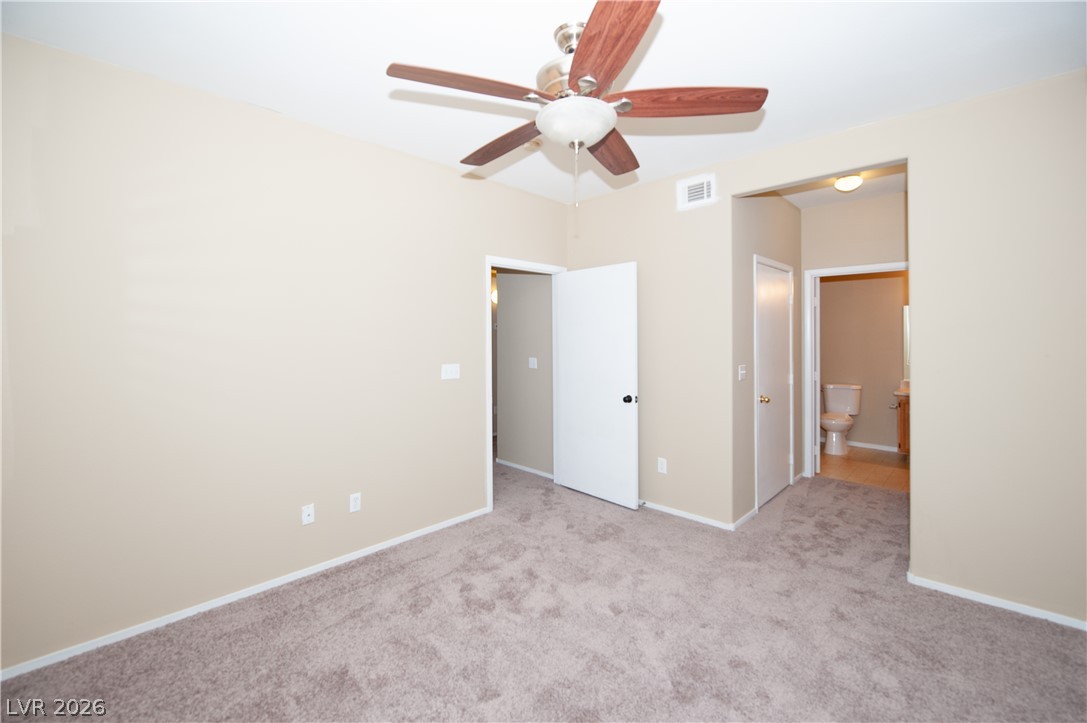 9050 West Warm Springs Road, Unit 1132 Las Vegas, NV 89148 - Photo 13 of 21 Well-appointed bedroom featuring a ceiling fan, plush carpeting, and access to a full bathroom.