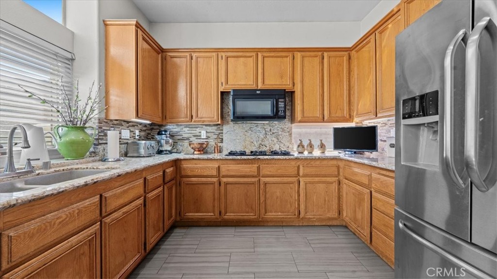 1671 Dominguez Ranch Road Corona, CA 92878 - Photo 17 of 42 his well-appointed kitchen includes ample counter space, a tile backsplash, and natural light from nearby windows, providing both style and practicality.