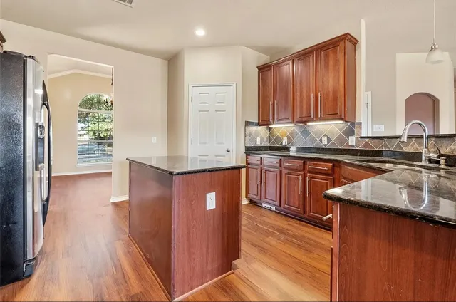 a kitchen with stainless steel appliances granite countertop wooden cabinets a sink and dishwasher with wooden floor