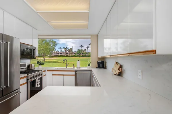 a kitchen with a sink a counter top space stainless steel appliances and a window