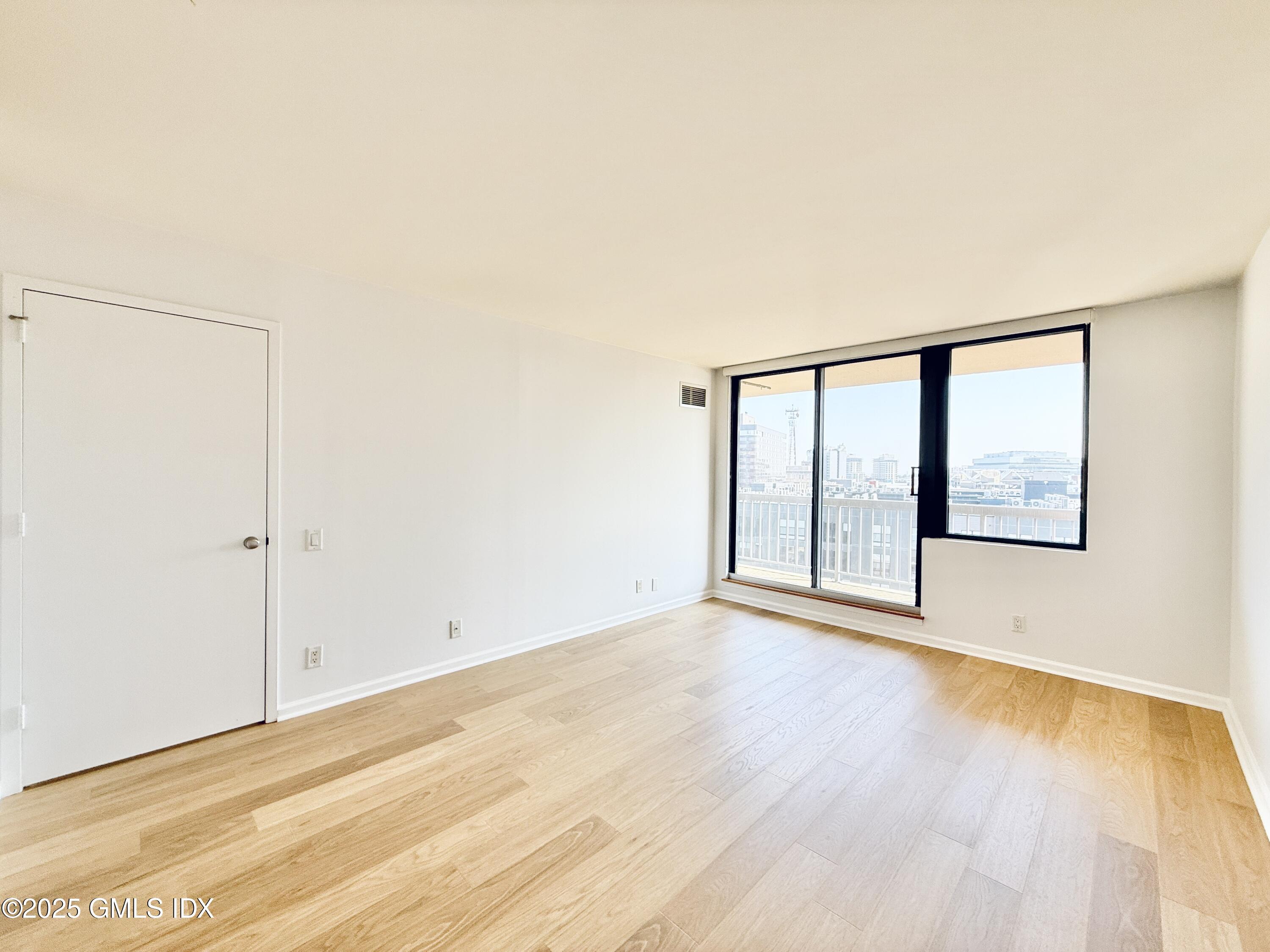 25 Forest Street, Unit 11M Stamford, CT 06901 - Photo 11 of 21 a view of an empty room with wooden floor and a window