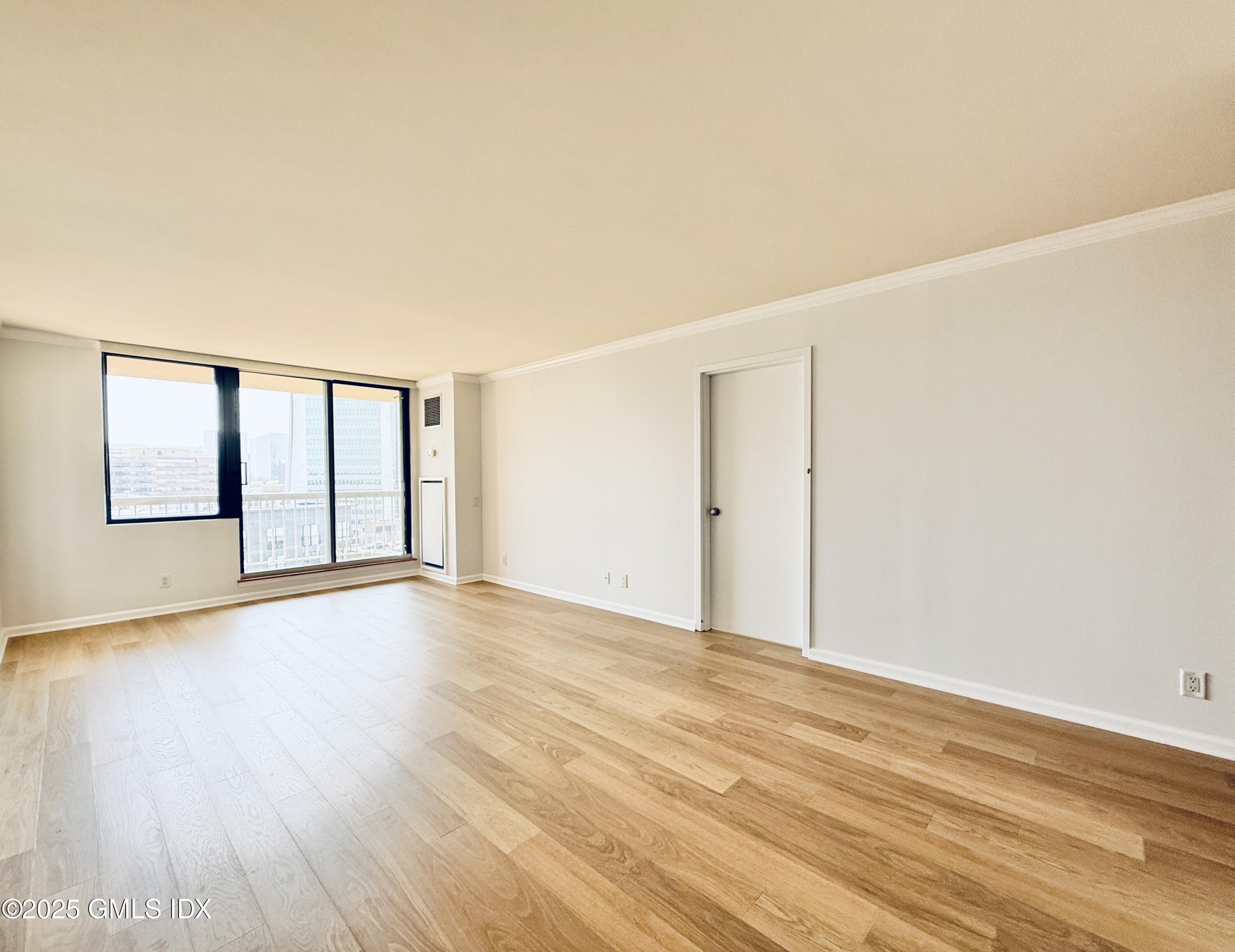 25 Forest Street, Unit 11M Stamford, CT 06901 - Photo 4 of 21 a view of an empty room with wooden floor and a window