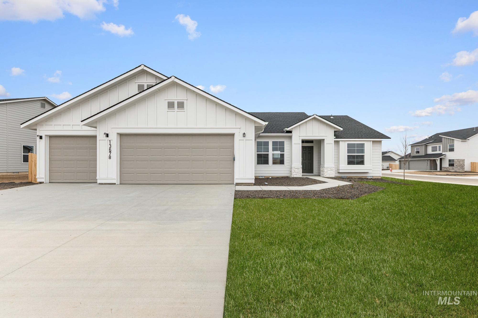 Modern inspired farmhouse with board and batten siding, a shingled roof, driveway, an attached garage, and a front lawn