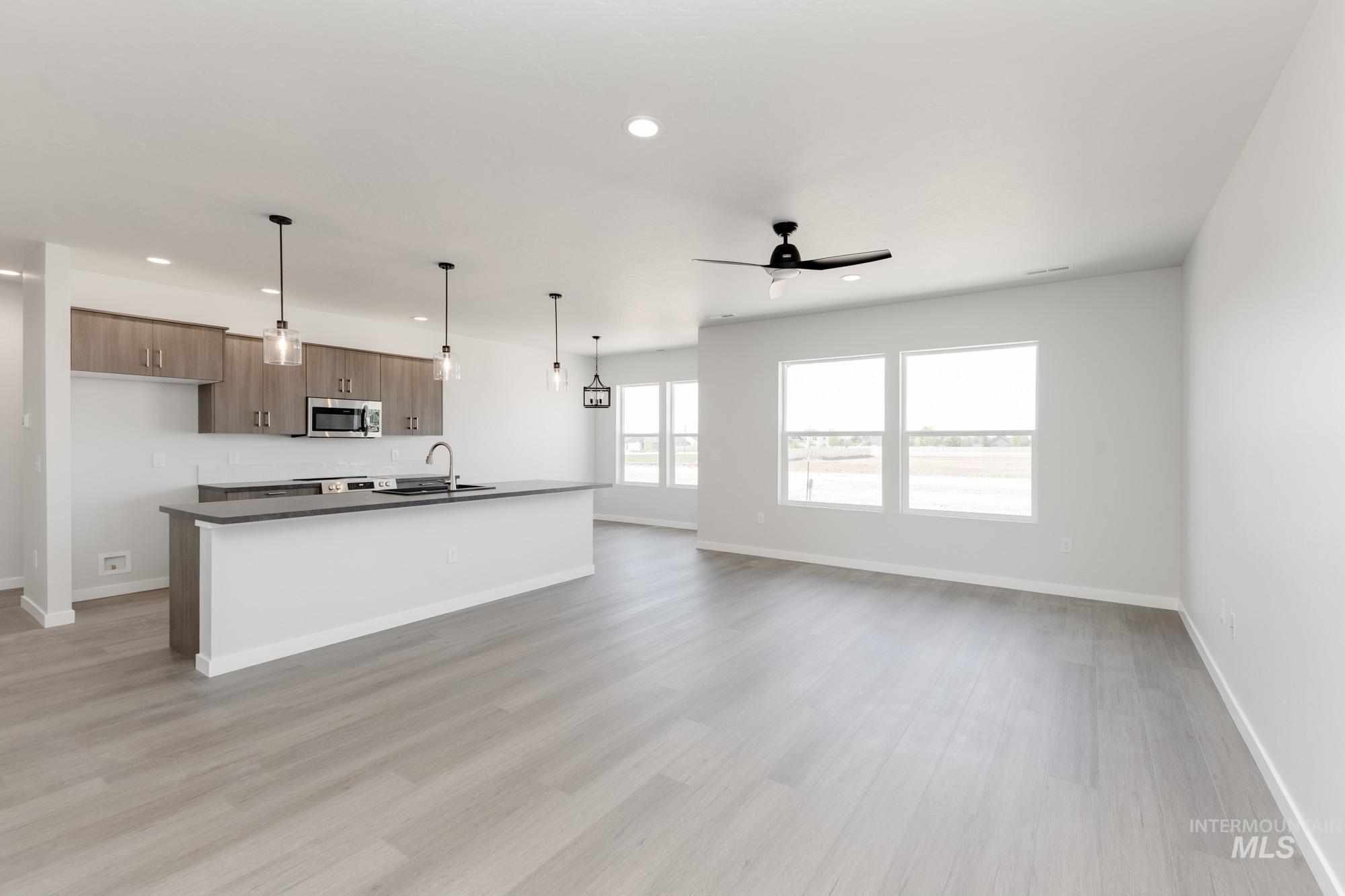 13678 Nisene Street Caldwell, ID 83607 - Photo 18 of 19 Kitchen with open floor plan, pendant lighting, an island with sink, a ceiling fan, and dark countertops