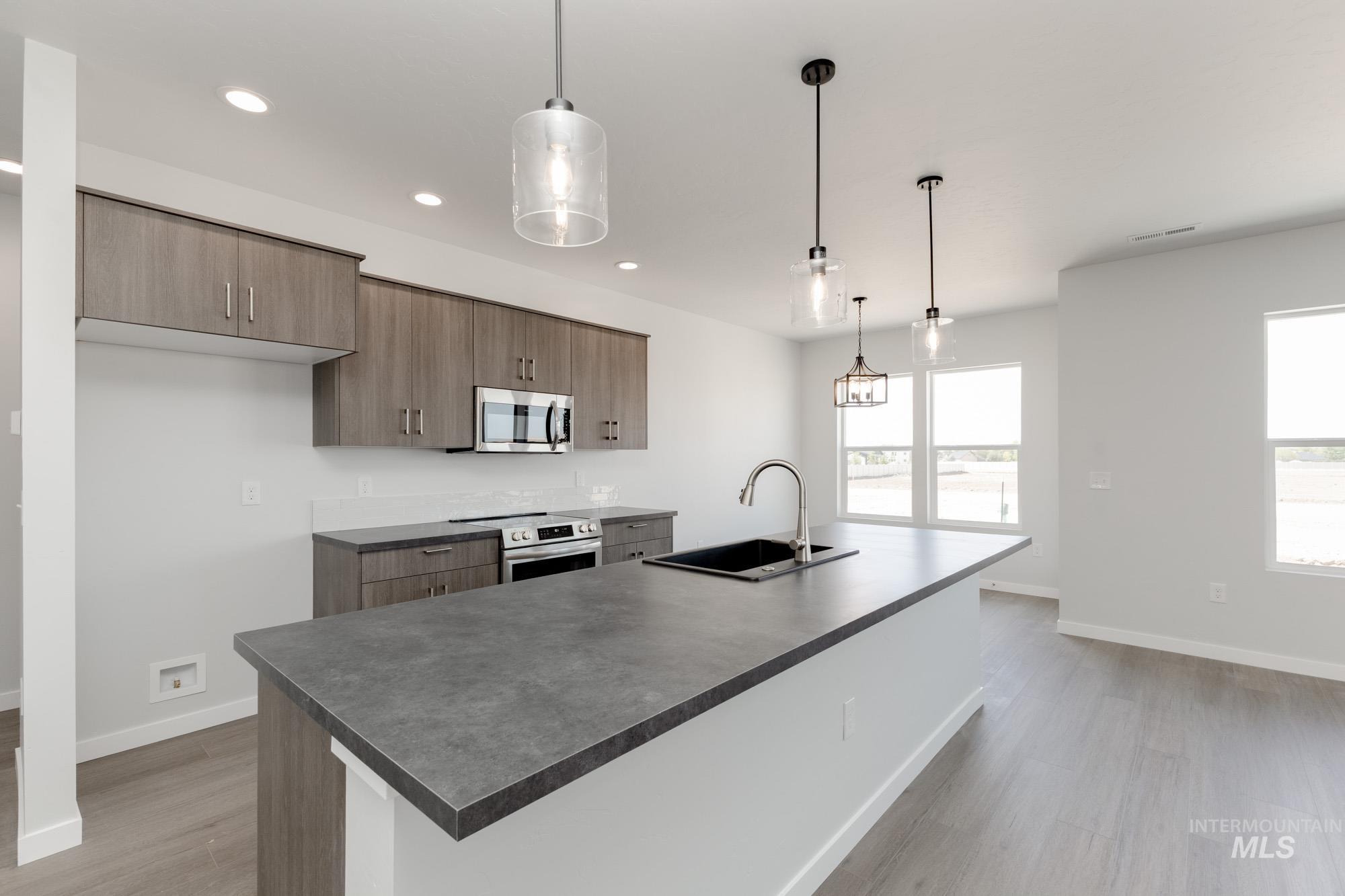 13678 Nisene Street Caldwell, ID 83607 - Photo 6 of 19 Kitchen with hanging light fixtures, appliances with stainless steel finishes, recessed lighting, a kitchen island with sink, and modern cabinets