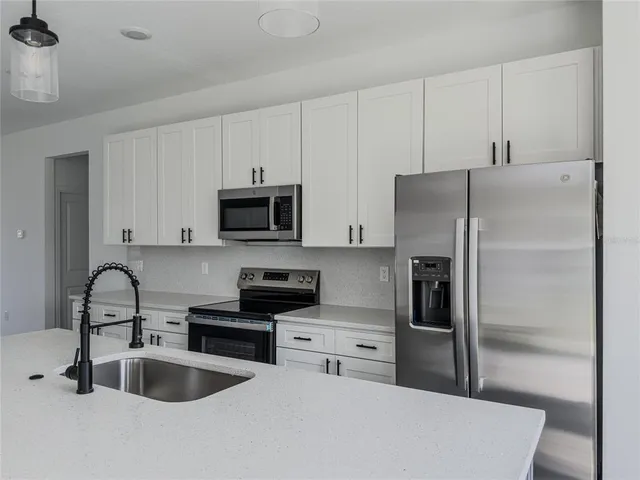 a kitchen with stainless steel appliances a refrigerator sink and white cabinets