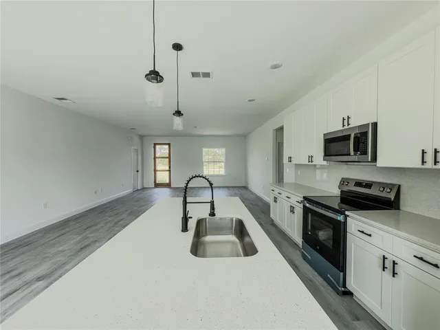 a kitchen with granite countertop a sink stainless steel appliances and white cabinets
