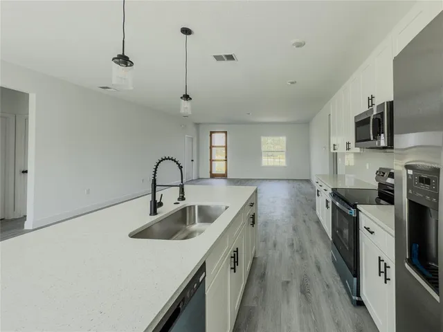 a kitchen with stainless steel appliances granite countertop a sink a stove and a refrigerator