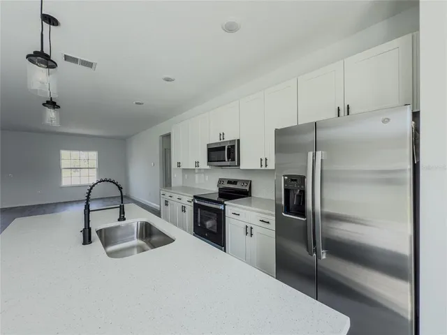 a kitchen with stainless steel appliances granite countertop a refrigerator sink and stove