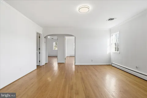 an empty room with a wooden floor and windows