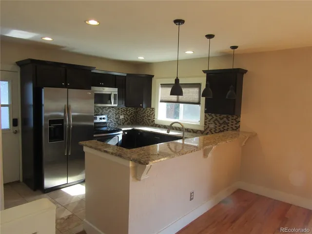 a kitchen with a refrigerator a sink and wooden floor