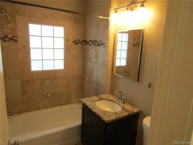 a bathroom with a granite countertop sink toilet and shower
