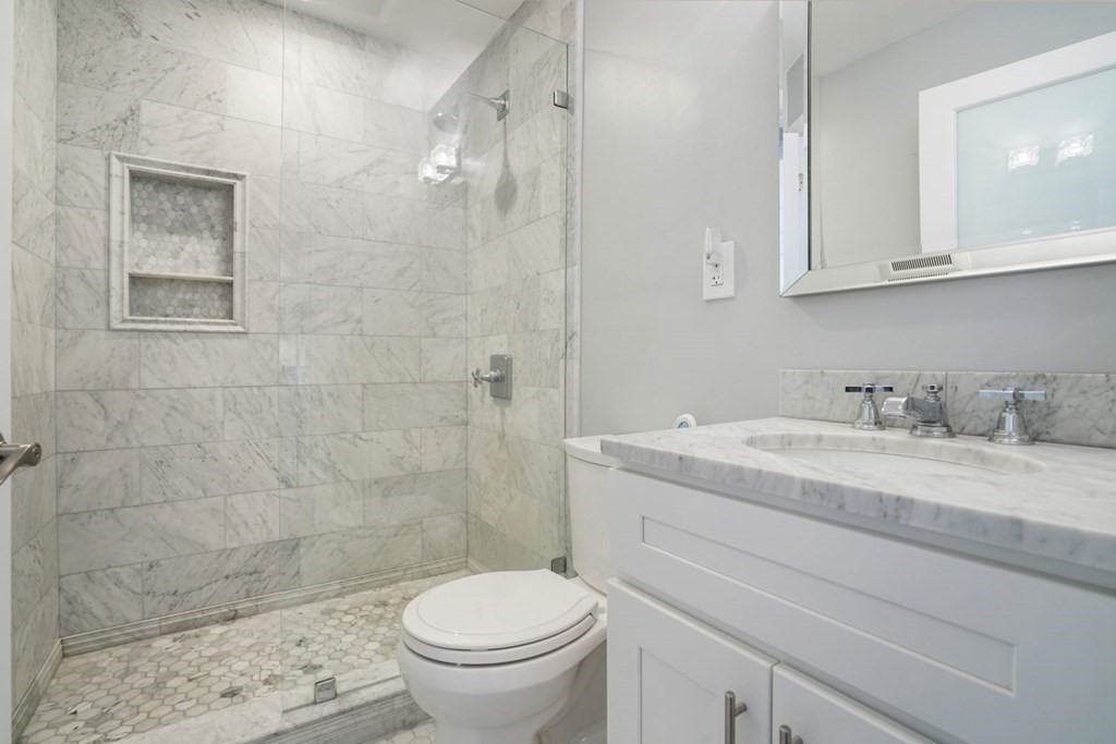 100 Captains Row, Unit 301 Chelsea, MA 02150 - Photo 9 of 23 a bathroom with a granite countertop sink a toilet and a shower