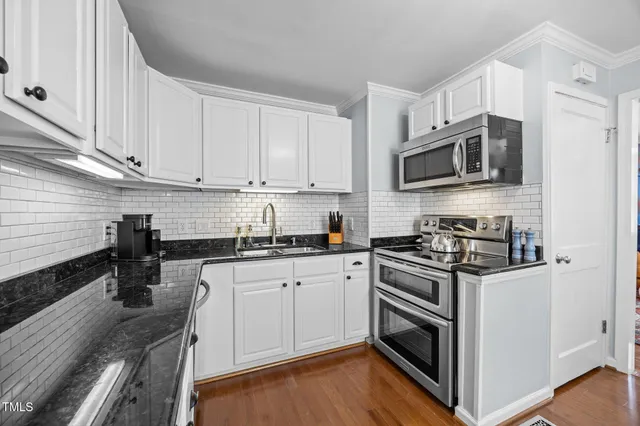a kitchen with granite countertop white cabinets and a sink