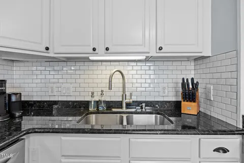 a kitchen with stainless steel appliances granite countertop white cabinets and black stove top oven with granite countertops