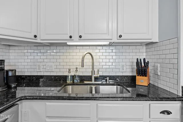 a kitchen with stainless steel appliances granite countertop white cabinets and black stove top oven with granite countertops