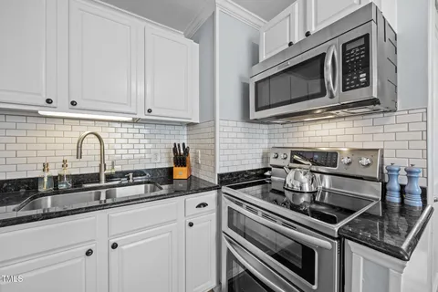 a kitchen with stainless steel appliances granite countertop a refrigerator a stove and a dining table with wooden floor