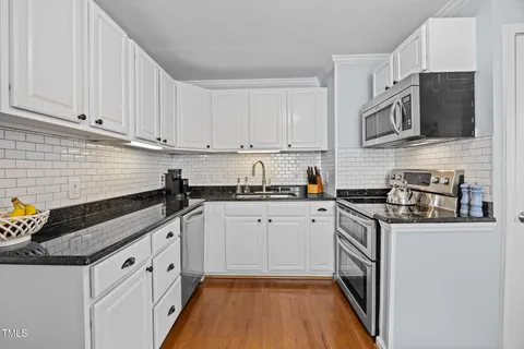 a kitchen with white cabinets a sink and dishwasher