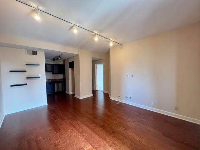 an empty room with wooden floor and a refrigerator