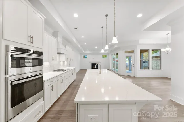 a large kitchen with kitchen island a stove a sink dishwasher and a oven with white cabinets