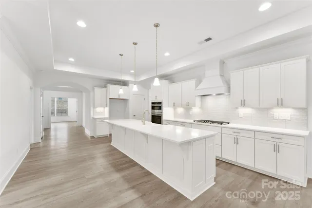 a large white kitchen with lots of counter space wooden floor and appliances