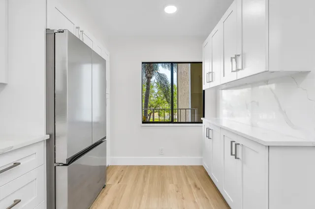 a kitchen with white cabinets and window