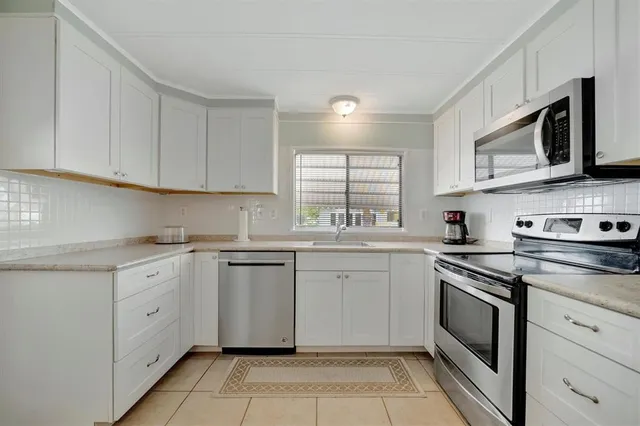a kitchen with granite countertop white cabinets stainless steel appliances and a sink