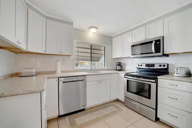 a kitchen with granite countertop white cabinets sink and stainless steel appliances