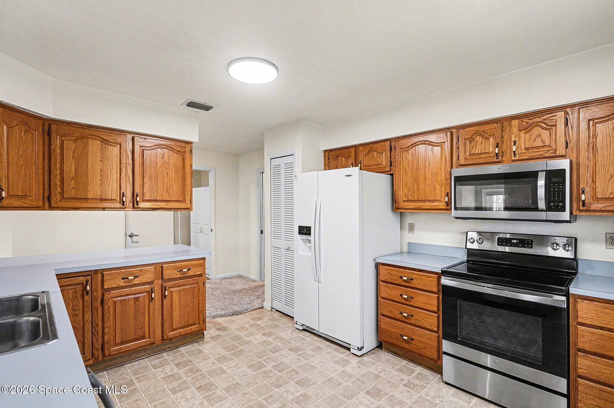 1741 Freedom Drive Melbourne, FL 32940 - Photo 12 of 37 a kitchen with stainless steel appliances a stove a refrigerator and a microwave