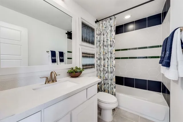 a bathroom with a sink a toilet a shower curtain and a large mirror