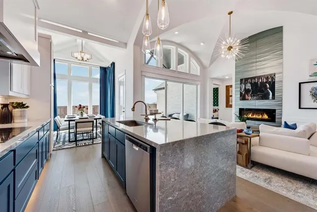 a large white kitchen with a large island oven a stove a sink a dining table and chairs