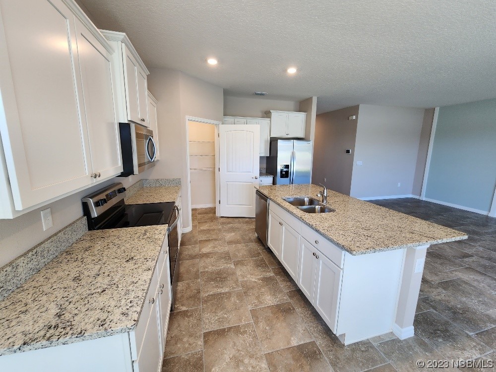 1839 Red Rock Road New Smyrna Beach, FL 32168 - Photo 3 of 23 a large kitchen with kitchen island granite countertop a large counter top and wooden floor