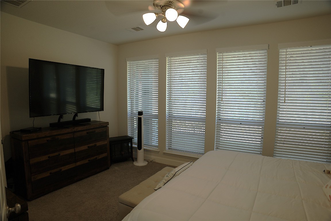 284 Kimble Creek Loop Kyle, TX 78640 - Photo 11 of 32 a bedroom with a bed and a flat screen tv