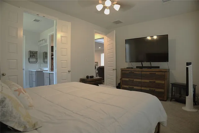 a bedroom with a bed and a flat tv screen on dresser