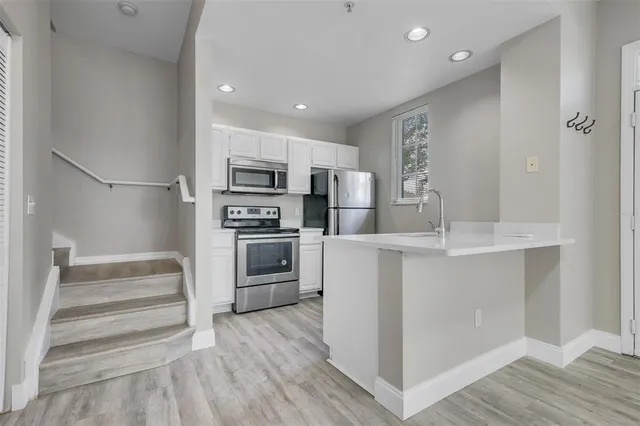a kitchen with kitchen island white cabinets and stainless steel appliances