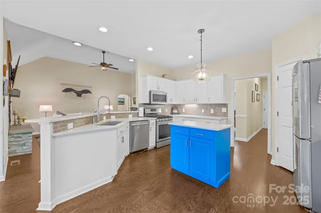 a large kitchen with stainless steel appliances sink refrigerator and cabinets