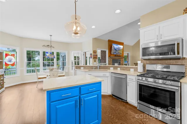 a open kitchen with granite countertop a stove top oven a sink dishwasher and a fireplace with wooden floor