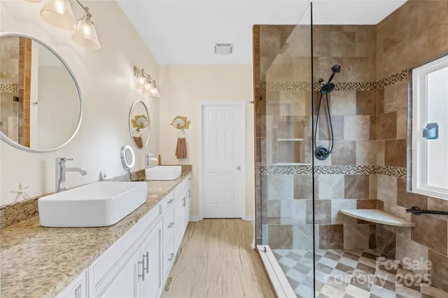 a bathroom with a granite countertop double vanity sink mirror and shower