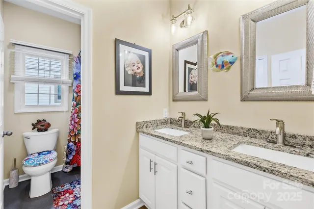 a bathroom with a granite countertop sink mirror and a toilet