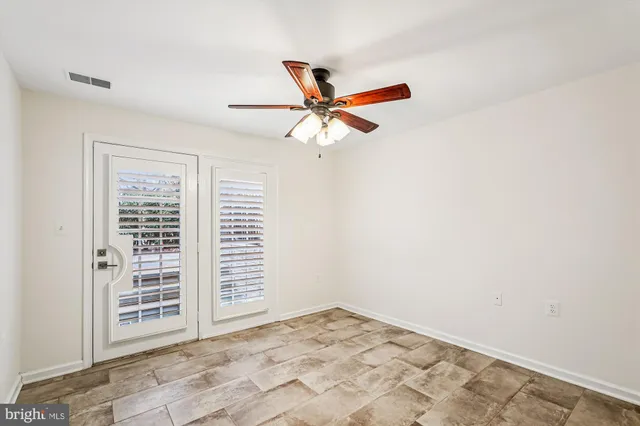 an empty room with windows and fan