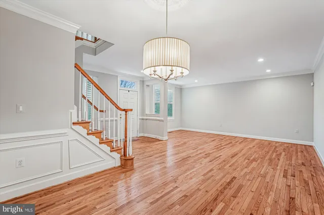 a view of empty room with wooden floor chandelier
