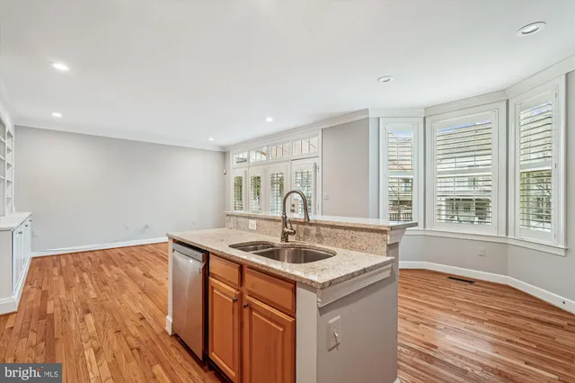 a kitchen with granite countertop wooden floors stainless steel appliances and sink
