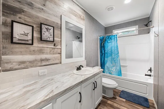 a bathroom with a granite countertop sink toilet and shower