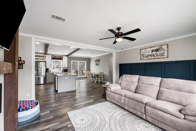 a living room with furniture kitchen view and a chandelier